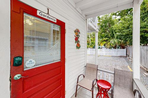 a red door and two chairs on a porch at Gardenia Getaway in Key West