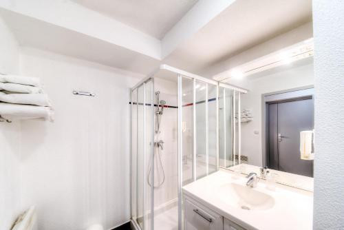 a white bathroom with a shower and a sink at Zenitude Hôtel-Résidences La City in Besançon