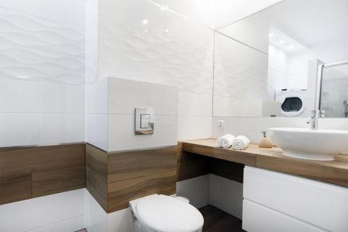 a white bathroom with a sink and a toilet at Good Time Apartments Kościelna 17 19 in Poznań
