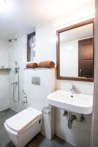 a bathroom with a sink and a toilet and a mirror at Hill Top Goa Lodge in Vagator