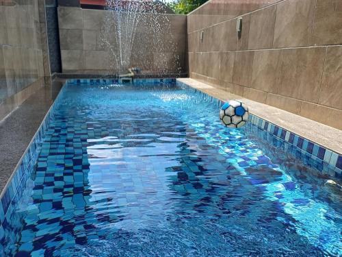 une piscine avec un ballon de foot et une fontaine dans l'établissement Lovely Cottage PD Staycation, à Port Dickson