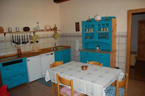 eine Küche mit blauen Schränken und einem Tisch mit Stühlen in der Unterkunft Andron in Solkan