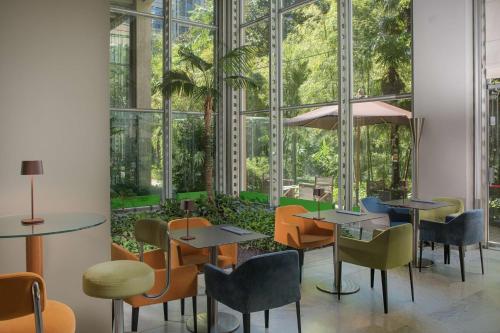a restaurant with tables and chairs and windows at NH Torino Lingotto Congress in Turin