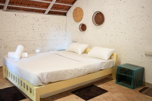 a bed with white sheets and pillows in a room at Nomad's Nook in Ponnampet