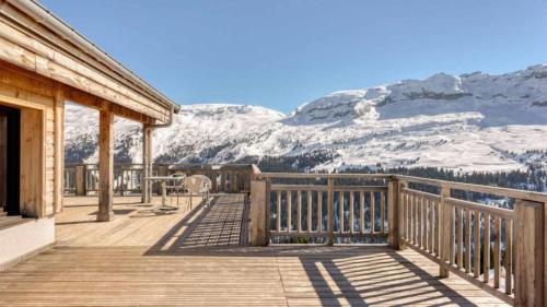 a wooden deck with snow covered mountains in the background at Résidence Les Portes du Grand Massif - Flaine in Flaine