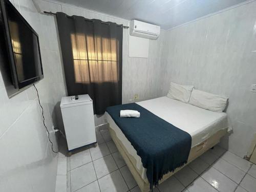 um pequeno quarto com uma cama e uma televisão em Pousada Casa Mar de Pajuçara em Maceió