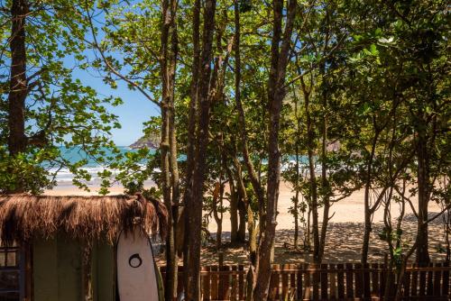 a surfboard parked next to a hut with a beach at Pousada Canto Bravo in Ilhabela