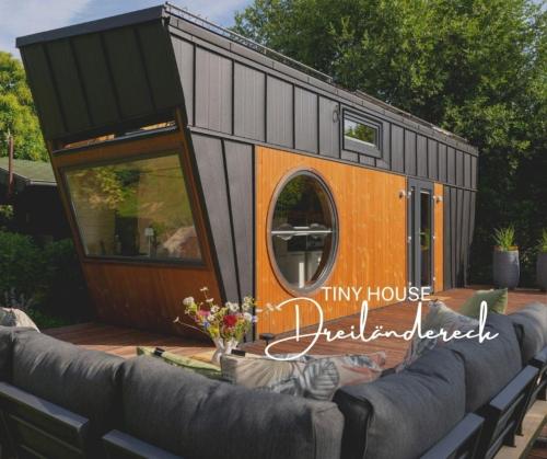 Una pequeña casa en una terraza con un sofá. en Tiny House Dreiländereck, en La Calamine