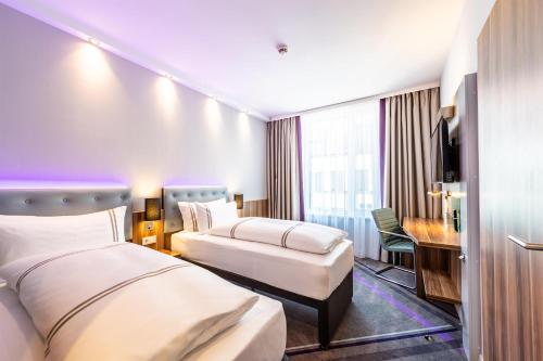 a hotel room with two beds and a desk at Premier Inn Dresden City Centre in Dresden