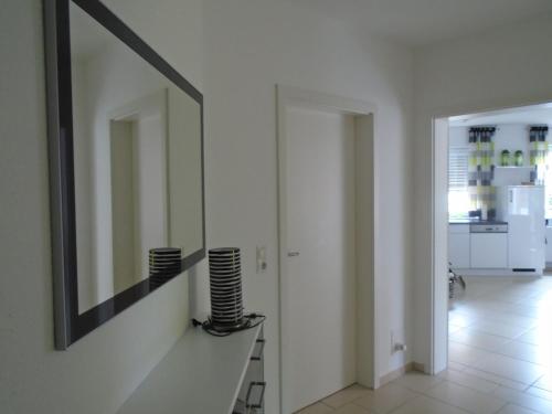 a mirror on the wall in a white hallway at Ferienwohnung Hilbers in Horumersiel