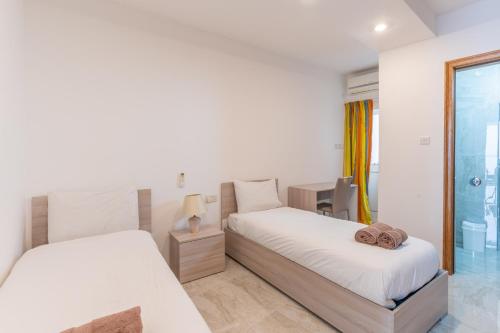 ein Schlafzimmer mit zwei Betten und einem Schreibtisch in der Unterkunft Cozy Apartment in Malta in St Paul's Bay