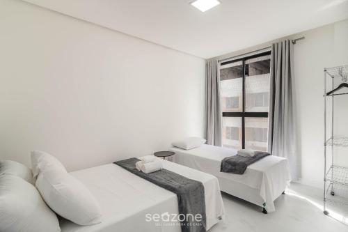 a white bedroom with two beds and a couch at Estadia completa a 500m do mar em Itapema - STWs in Meia Praia