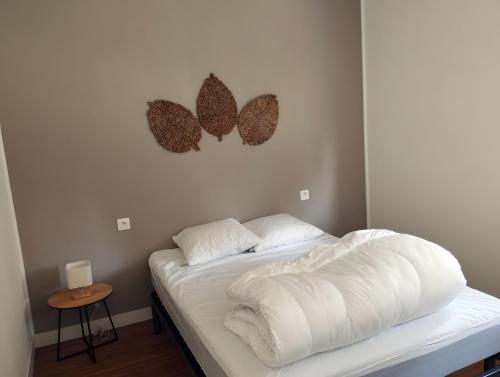 a bed with a white comforter in a room at Les Petits Cailloux in Saint-Martin-lʼAstier