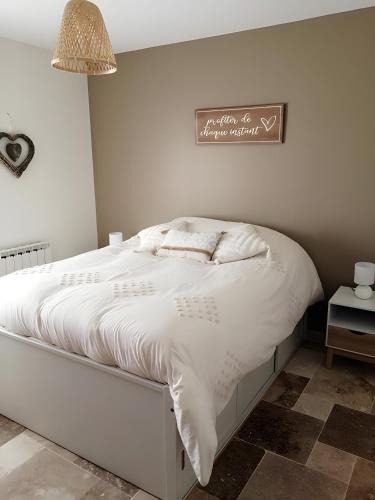 Una cama blanca con sábanas y almohadas blancas. en Appartement La Pierre, en Saint-Martin-lʼAstier