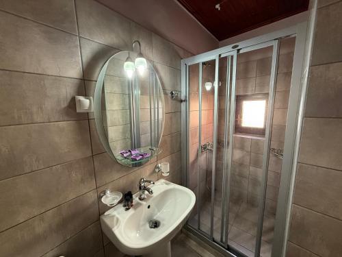 Un baño con lavabo, ducha y espejo. en Helena Hotel, en La Canea