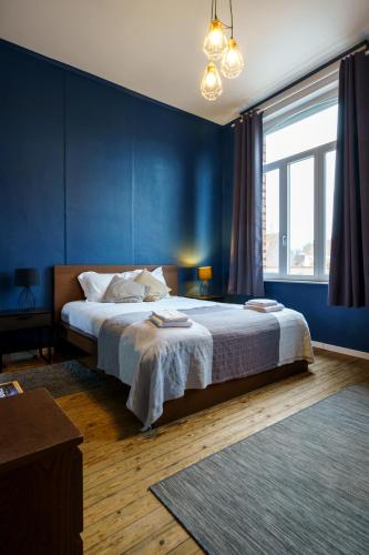 a bedroom with a large bed with blue walls at The Canal View Suites in Bruges