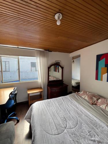 ボゴタにあるHabitaciones junto a Universidad del Bosqueの木製の天井と大きなベッドのある寝室