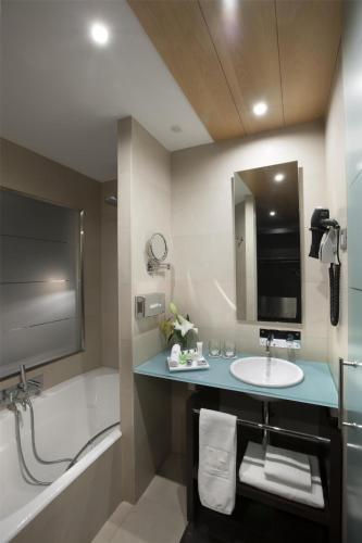 a bathroom with a sink and a bath tub and a bath tub at NH Collection Sevilla in Seville
