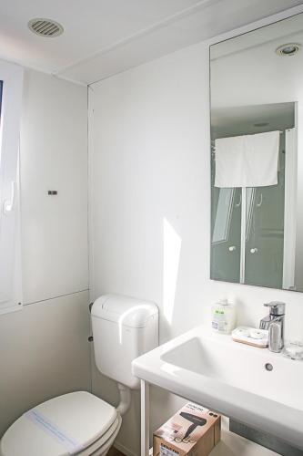 a white bathroom with a toilet and a sink at Auto-kamp Dvije suze 3 in Brištane