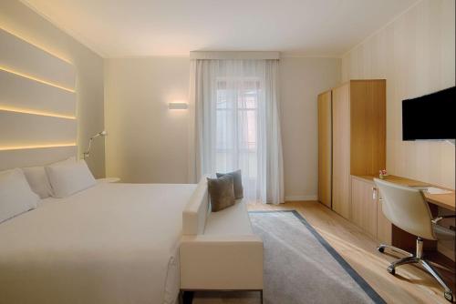 a hotel room with a large white bed and a desk at NH Collection Torino Santo Stefano in Turin