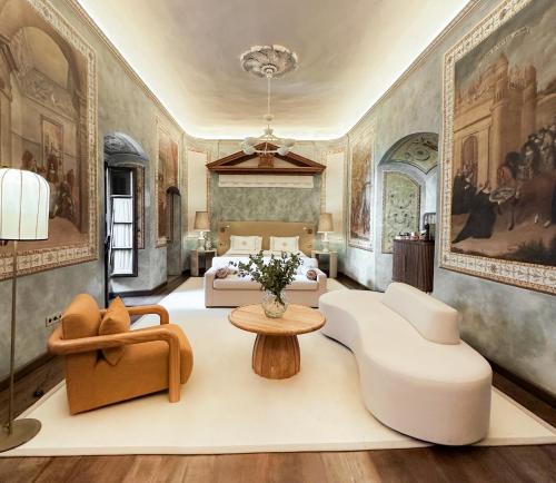 a bedroom with a bed and a couch and chairs at Hospes Palacio del Bailio, a Member of Design Hotels in Córdoba