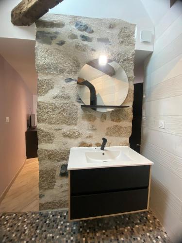 a bathroom with a sink and a stone wall at Gîte de Vareilles in Cantoin
