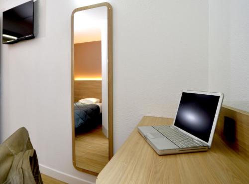 a laptop sitting on a table in front of a mirror at Premiere Classe Dunkerque Loon Plage in Loon-Plage