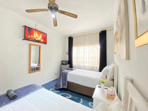 ein Schlafzimmer mit zwei Betten und einem Deckenventilator in der Unterkunft Terrys Cozy Homestay in Germiston