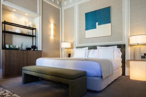 a bedroom with a large white bed and a bench at Hospes Palacio de los Patos, a Member of Design Hotels in Granada