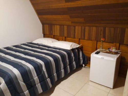 a bed with a blue and white striped blanket in a room at Chalés Dinhá-Pousada Recanto do Rapa in Brumadinho