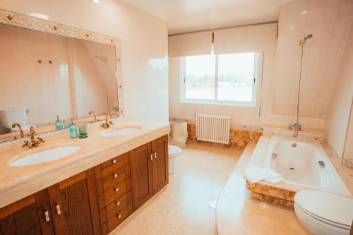 ein Badezimmer mit zwei Waschbecken und einer Badewanne und einer Toilette in der Unterkunft Villa Nora in Sanxenxo