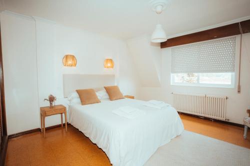 ein weißes Schlafzimmer mit einem weißen Bett und einem Fenster in der Unterkunft Villa Nora in Sanxenxo