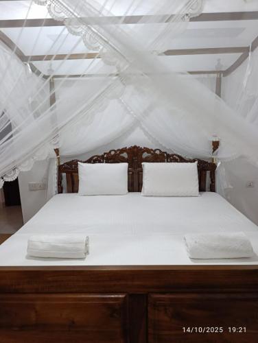 a large bed with white sheets and pillows on it at Villa Senowin in Anuradhapura