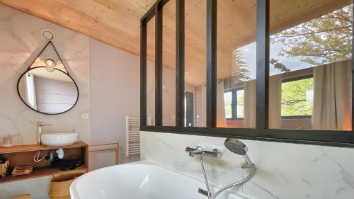 La salle de bains est pourvue d'une baignoire blanche et d'un miroir. dans l'établissement La villa Grand Ouest, à Plounéour-Trez