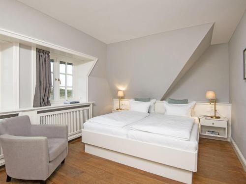 a white bedroom with a bed and a chair at Prahl-Hues-1 in Kampen