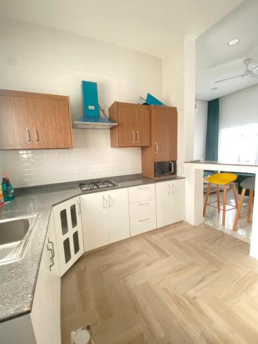 cocina con armarios blancos y suelo de madera en شاليه ڤيو, en Al Hadd