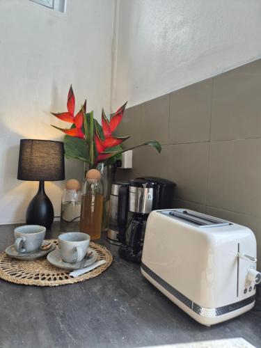 a counter with a toaster and two cups on a table at La villa detente 1 - une experience authentique in Rodrigues Island