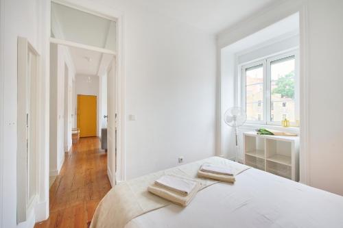 a white bedroom with two towels on a bed at Cozy Apartment with Castel view in Lisbon