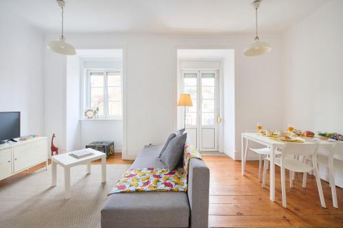 a white living room with a couch and a table at Cozy Apartment with Castel view in Lisbon