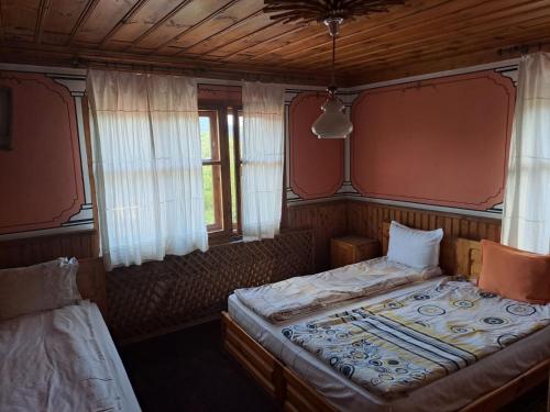 a bedroom with two beds and two windows at Карагьозовата Къща - цяла къща - 6 големи спални, 6 бани и отделна механа in Koprivshtitsa