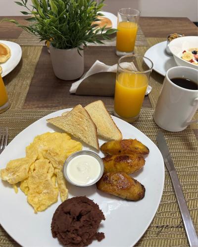 un piatto di prodotti per la colazione con pane tostato, pane e succo d'arancia di Agenda Hotel a San Salvador
