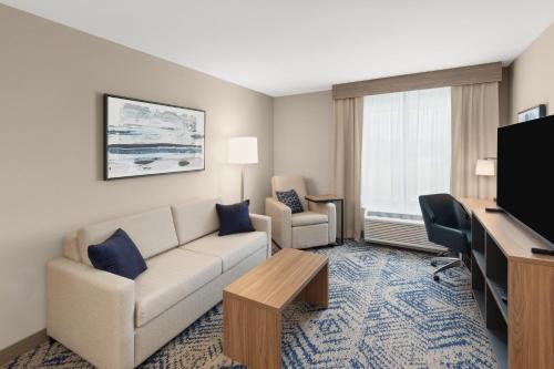 a living room with a couch and a flat screen tv at Candlewood Suites Huntsville - Research Park by IHG in Huntsville