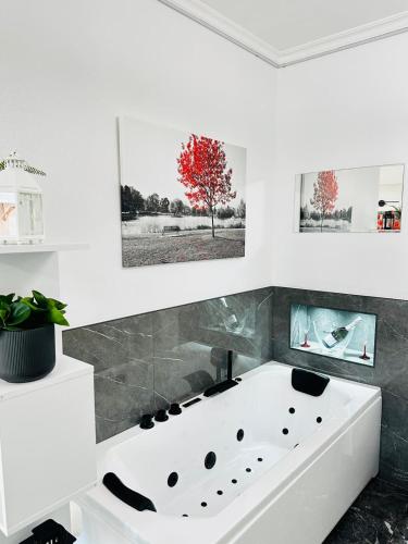 a white bath tub in a white room with paintings at Suite AeF Lido di Ostia in Lido di Ostia