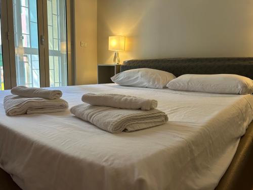 two towels on a white bed with pillows on it at Giaco Symphony Stay in Bari
