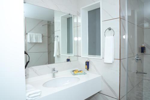 a white bathroom with a sink and a mirror at Faletti's Boutique Multan in Dargai