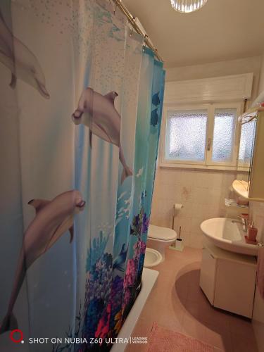 a bathroom with a shower curtain with dolphins on it at Atlantis Apartment Trieste in Trieste