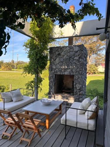 eine Terrasse mit einem Steinkamin und einem Tisch und Stühlen in der Unterkunft Casa Río Mío in Colonia del Sacramento