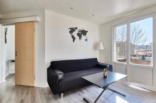 a living room with a black couch and a world map on the wall at Saint maurice RER A direct Disney in Joinville-le-Pont