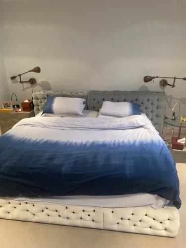 a large bed with a blue comforter and two pillows at 1 callcoot Road in London
