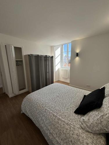 a bedroom with a bed with a black pillow on it at Appartement moderne proche de l'autoroute in Combronde